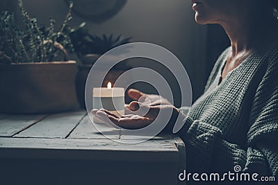 Woman at home in zen meditation activity and candlelight in background. One female people with hands up pray or meditate alone in Stock Photo