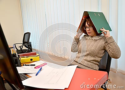 The woman with horror looks in the monitor, holding the folder with documents on the head Stock Photo