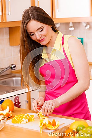 Woman housewife in kitchen cutting orange fruits Stock Photo