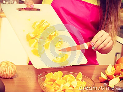 Woman housewife in kitchen cutting orange fruits Stock Photo