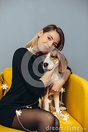 Woman hug puppy of beagle on yellow chair Stock Photo