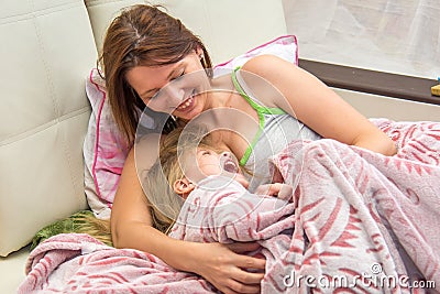 A woman hugs little daughter in bed waking up Stock Photo