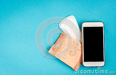 Woman hygiene protection. Sanitary pads and mobile phone on blue background. Menstrual cycle tracking Stock Photo