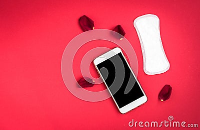 Woman hygiene protection or sanitary pads with rose petals and mobile phone on red background. Menstrual cycle tracking Stock Photo