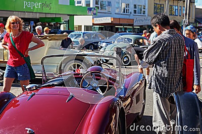 Woman impressed by a red sports car at a vintage car show in Motueka High Street in front of the museum Editorial Stock Photo