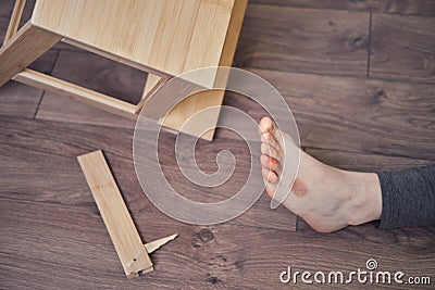 Woman injured foot on leg after falling from wooden stepladder. The problem with labor protection at diy work at home Stock Photo