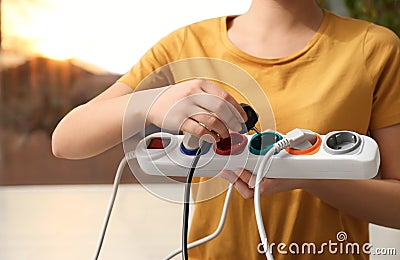 Woman inserting power plug into extension cord, closeup. Electrician`s professional equipment Stock Photo