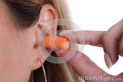 Woman inserts orange earplugs into ears closeup Stock Photo