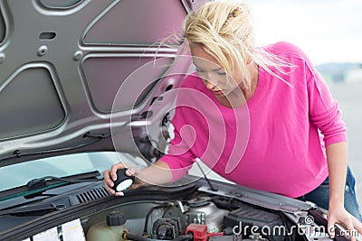 Woman inspecting broken car engine. Stock Photo