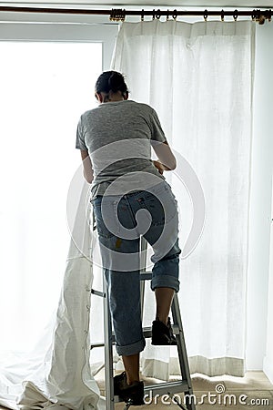 A woman installing window curtain Stock Photo