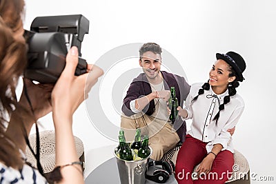 Woman with instant camera photographing happy young couple drinking beer together Stock Photo