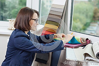 Woman interior designer, works with samples of fabrics for curtains and blinds. Stock Photo