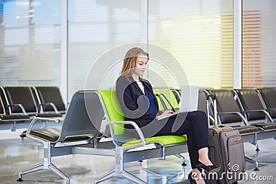 Woman in international airport terminal, working on her laptop Stock Photo