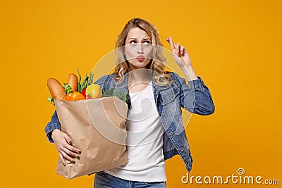 Woman isolated on orange background. Delivery service from shop or restaurant concept. Hold brown craft paper bag for Stock Photo