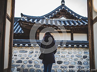 A woman in jacket opening the door in Namsangol Hanok Village on a fine weather Editorial Stock Photo