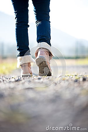 Woman in jeans and boots walking along a rural path Stock Photo