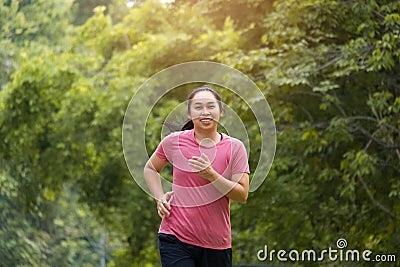 Woman jogging in the park in the sunshine on a beautiful summer day. Beautiful young woman jogging training exercise. Healthy Stock Photo