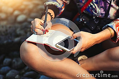 Woman journalist reporter with camera takes notes on a notebook Stock Photo