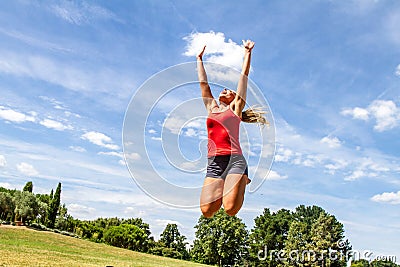 Woman jumping high to reach the sky in green park Stock Photo