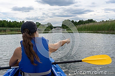 Woman in a kayak on a beautiful lake points to the reeds and shore Stock Photo