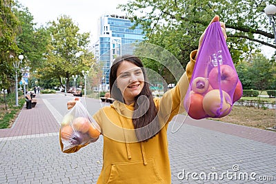 The woman keeps vegetables and fruits in a plastic bag and a cloth shopper. Stock Photo