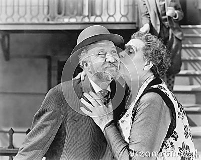 Woman kissing a man on his cheek Stock Photo