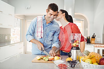 Woman kissing man preparing fruit juice Stock Photo