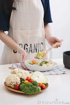 Woman in kitchen cooking stir vegetables on pan and tasting Stock Photo