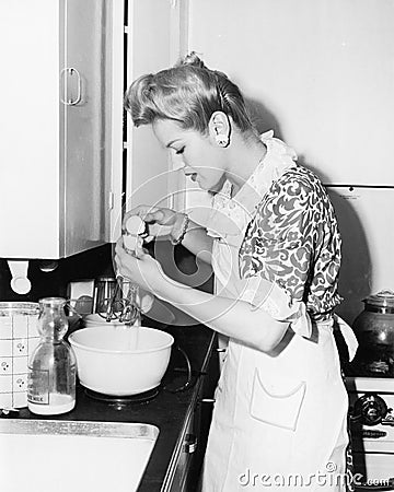 Woman in the kitchen cracking an egg Stock Photo