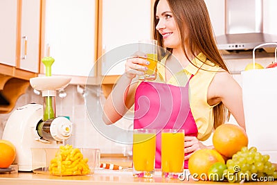 Woman in kitchen drinking fresh orange juice Stock Photo