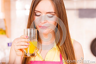 Woman in kitchen drinking fresh orange juice Stock Photo