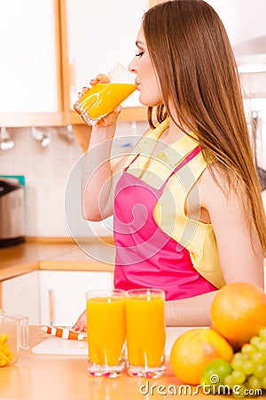 Woman in kitchen drinking fresh orange juice Stock Photo