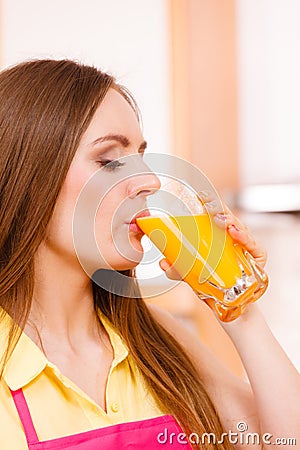 Woman in kitchen drinking fresh orange juice Stock Photo