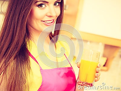 Woman in kitchen drinking fresh orange juice Stock Photo