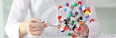 Woman in laboratory coat demonstrates model of molecule Stock Photo
