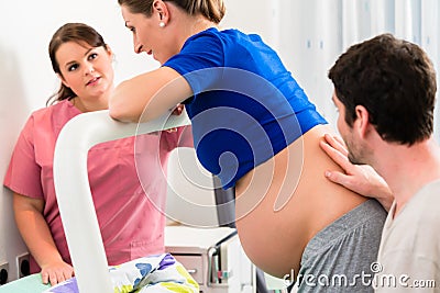 Woman laboring in delivery room with nurse and husband Stock Photo