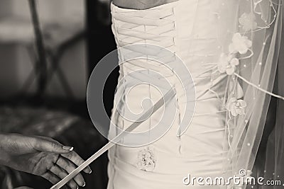 Woman lace up a corset on the delicate bride's waist Stock Photo