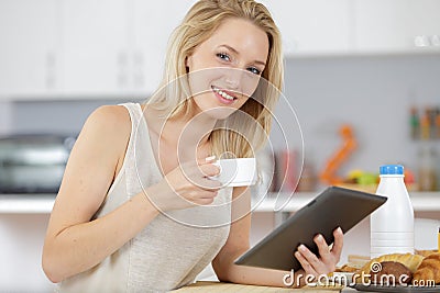 woman laughing at kitchen table with coffee and tablet Stock Photo