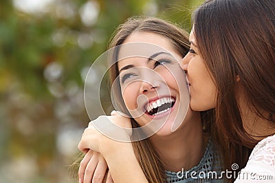 Woman laughing with perfect teeth while a friend is kissing her Stock Photo