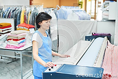 Woman Laundry worker pats the linen on the automatic machine Stock Photo