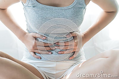 Woman laying on the bed suffering from abdominal pain. female suffering from period on the bed Stock Photo