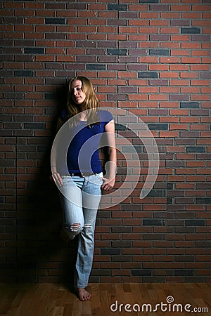 Woman leaning against brick wall Stock Photo