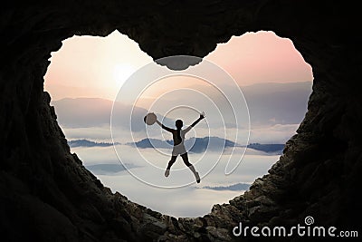 Woman leaps inside cave at mountain Stock Photo