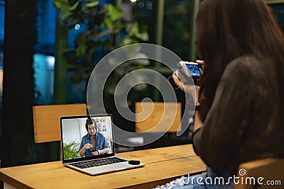 Asian female watching online training workshops for camera function by notebook in the living room Stock Photo