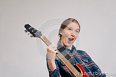 A woman learns to play the electronic guitar. young rocker plays a musical instrument. Screaming during a song Stock Photo