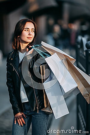 Woman in leather jacket carrying many paper bags Stock Photo