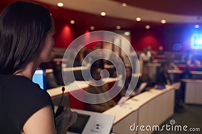 Woman lecturing students in lecture theatre, focus foreground Stock Photo