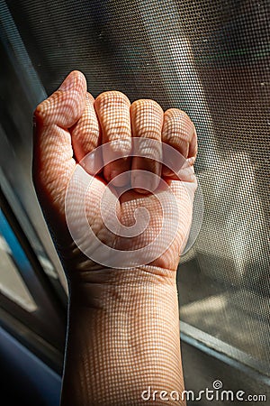 Woman left hand in fist with dust Dirty mosquito wire screen window, Light & Shadow shot, Close up shot Stock Photo