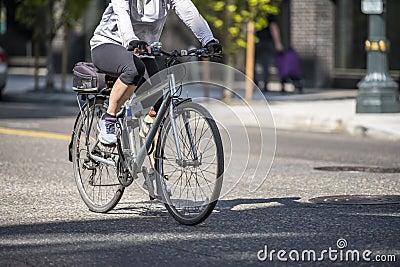 Woman in leggings and gloves makes a bike ride traveling along the road along the street of a modern city Stock Photo