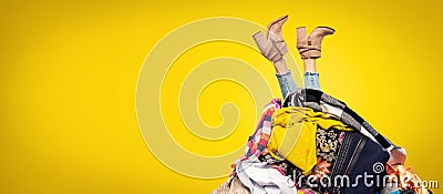 Woman legs out of clothes pile on yellow background Stock Photo